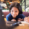 Child writing in front of computer
