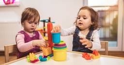 Two toddlers in daycare engaging in a play based approach to learning by stacking cups