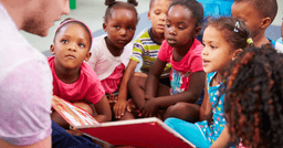 Image of children listening to their teacher read them a book that helps them understand cultural experiences