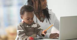A childcare director working on admin tasks while also trying to help in the room