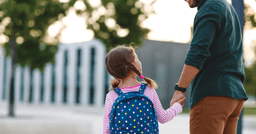 A preschooler getting dropped off on their first day saying goodbye to their parent