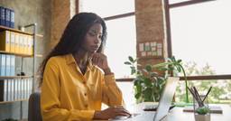 Side profile of a childcare director working at her computer in office during tax season