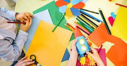 Desk in preschool classroom covered in process art supplies that children are using.