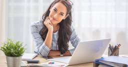 Early childhood educator sitting at computer and smiling at the camera